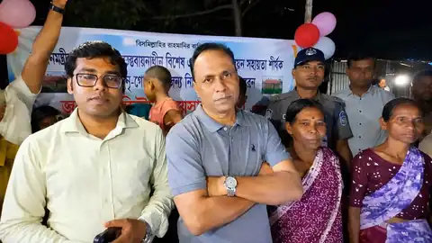 রাতের অনুষ্ঠানে ব্যারিস্টার কায়সার কামাল স্থানীয় নারী-পুরুষের সঙ্গে, পেছনে ব্যানার ও বেলুন